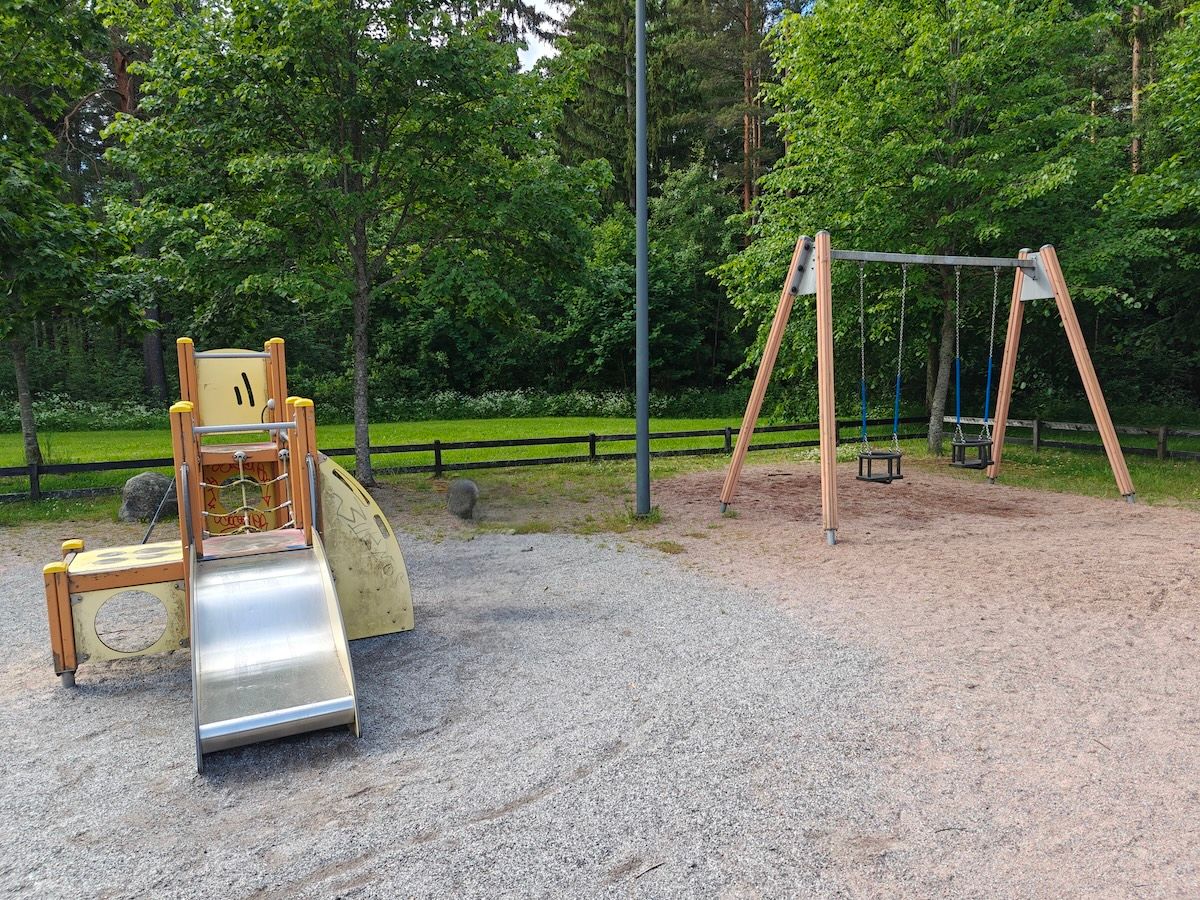 Pieni kiipeilyteline, jossa liukumäki, sekä kaksi vauvakeinua.
