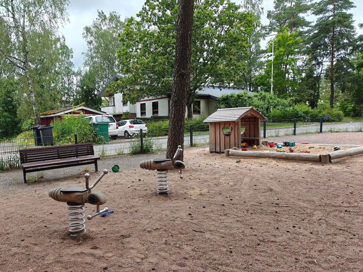 Kaksi jousivälinettä ja hiekkalaatikko pienellä mökillä.