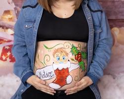 Mujer embarazada con un diseño de bellypainting navideño