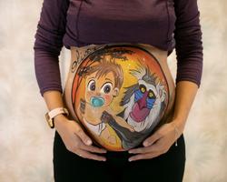 Mujer embarazada posando con diseño de bellypainting de rafiki elevando a un bebé