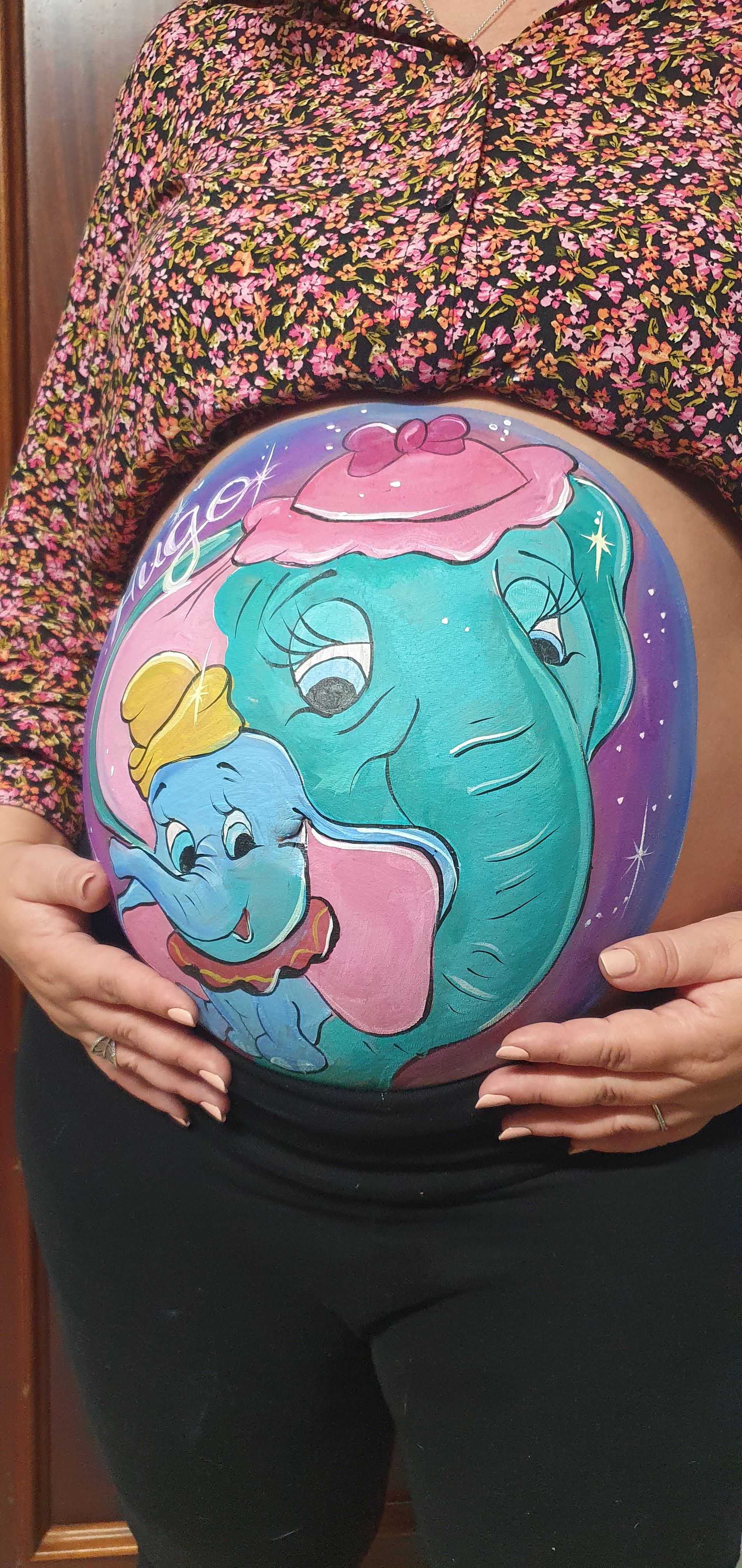 Mujer embarazada posando con diseño de bellypainting  de dumbo y su mama
