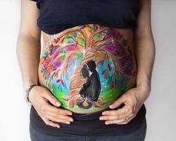Diseño de bellypainting personalizado, muy colorido con un árbol de la vida y una silueta de un hombre y una mujer embarazada