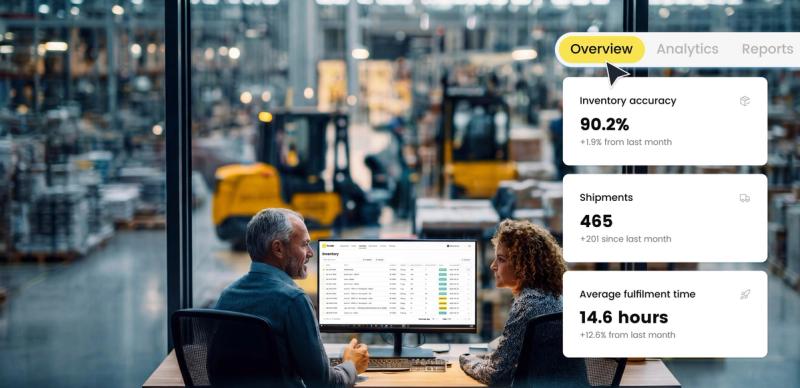 Two colleagues review a warehouse inventory dashboard on a monitor, with overview stats overlaid showing accuracy,