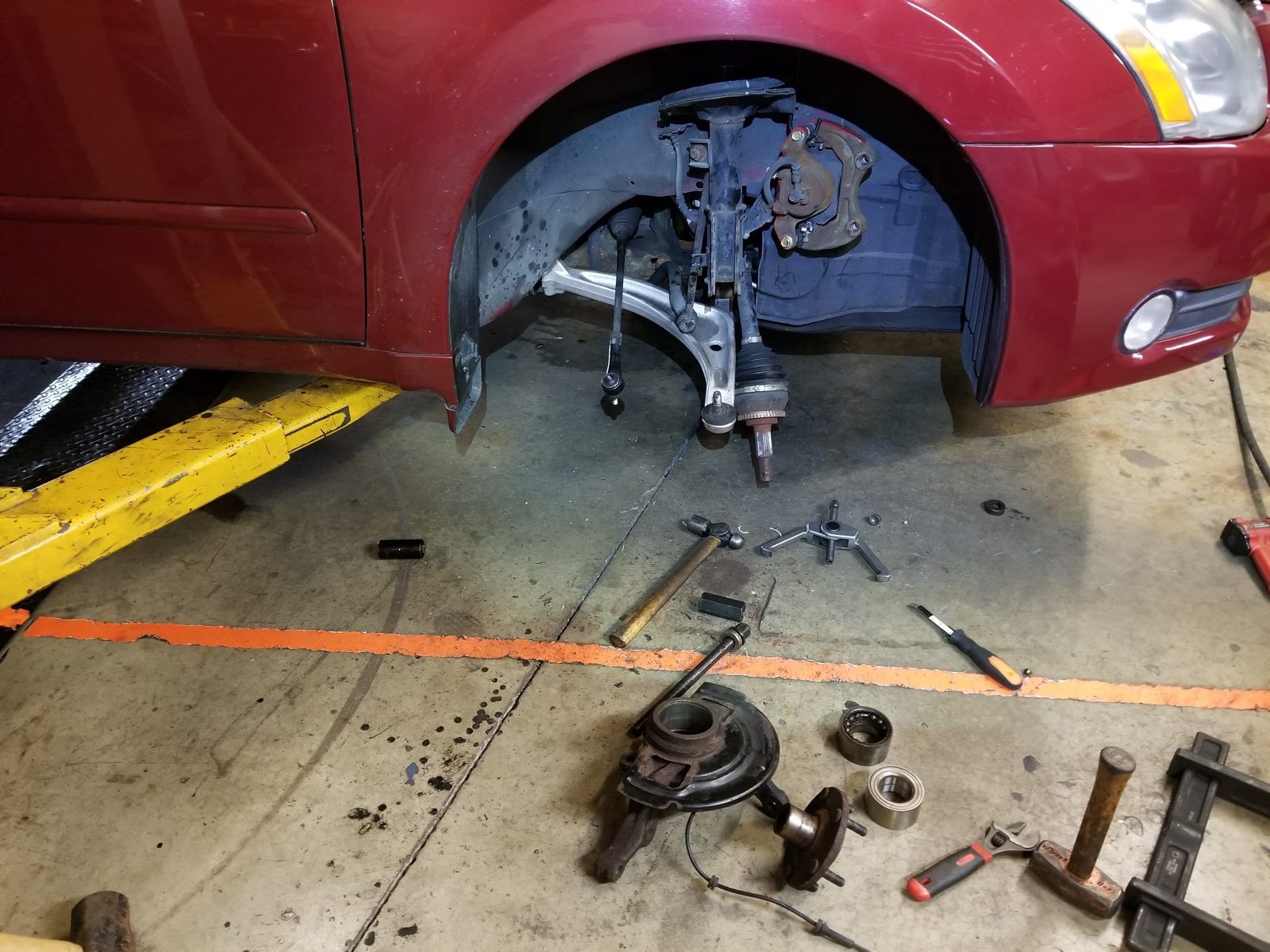 Front suspension and hub assembly removed from a minivan with control arm and bearing on the floor at Speedy Underhood Service in Columbus, Ohio