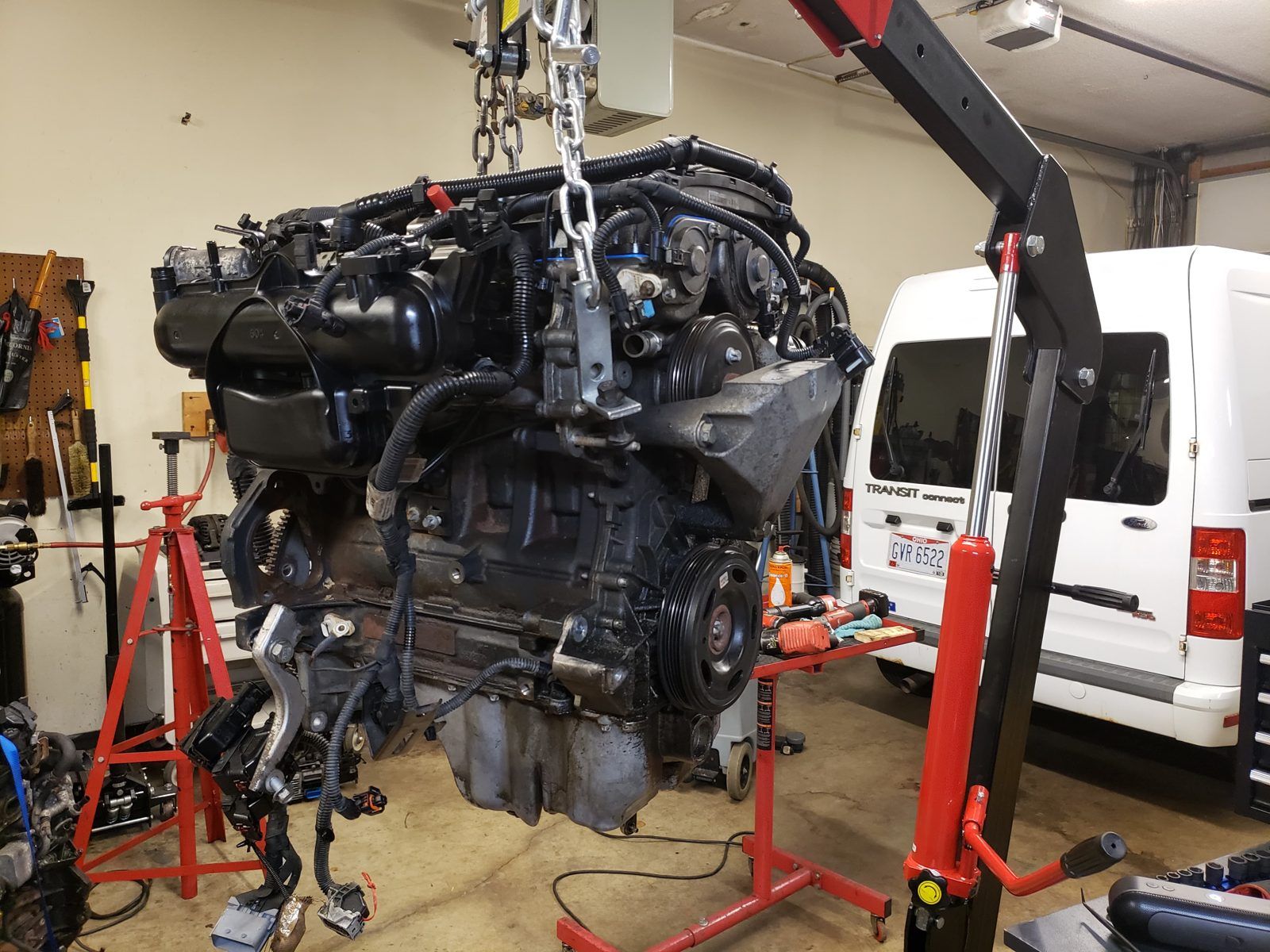 Engine hanging from an engine crane with accessories and wiring still attached at Speedy Underhood Service in Columbus, Ohio
