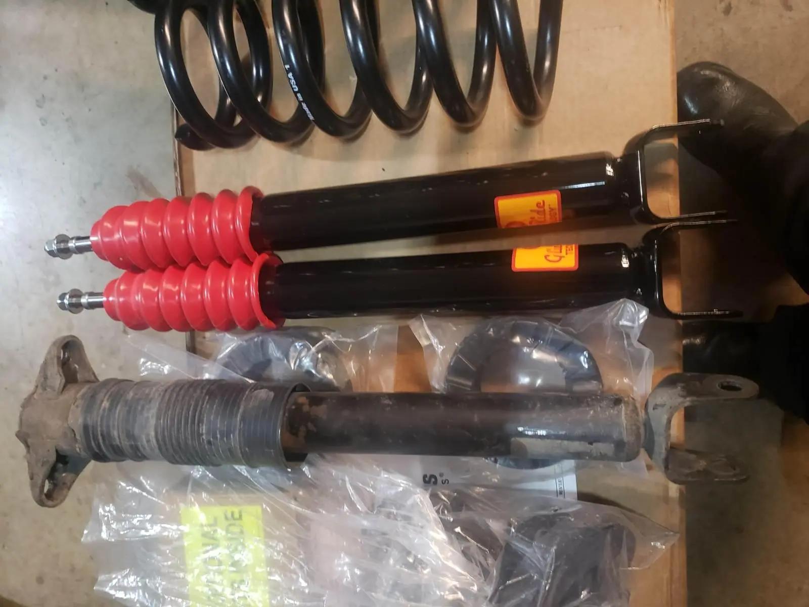 New shock absorbers, coil spring and mounting hardware laid out beside the worn original strut at Speedy Underhood Service in Columbus, Ohio