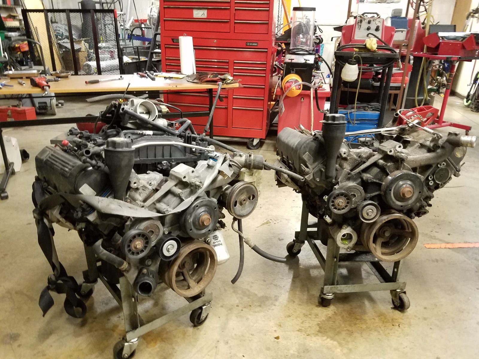 Two V6 engines on rolling stands beside the tool chest during engine replacement work at Speedy Underhood Service in Columbus, Ohio