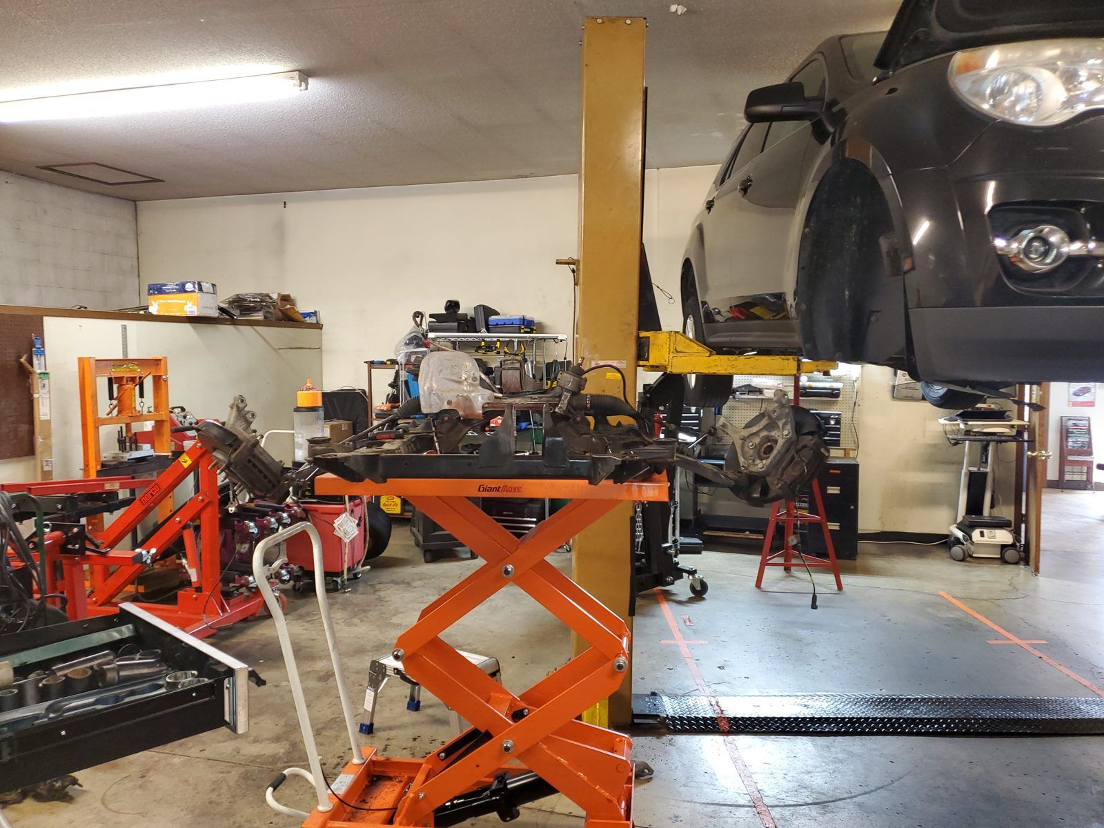 Service bays with a vehicle on the lift and transmission jacks staged for a driveline job at Speedy Underhood Service in Columbus, Ohio