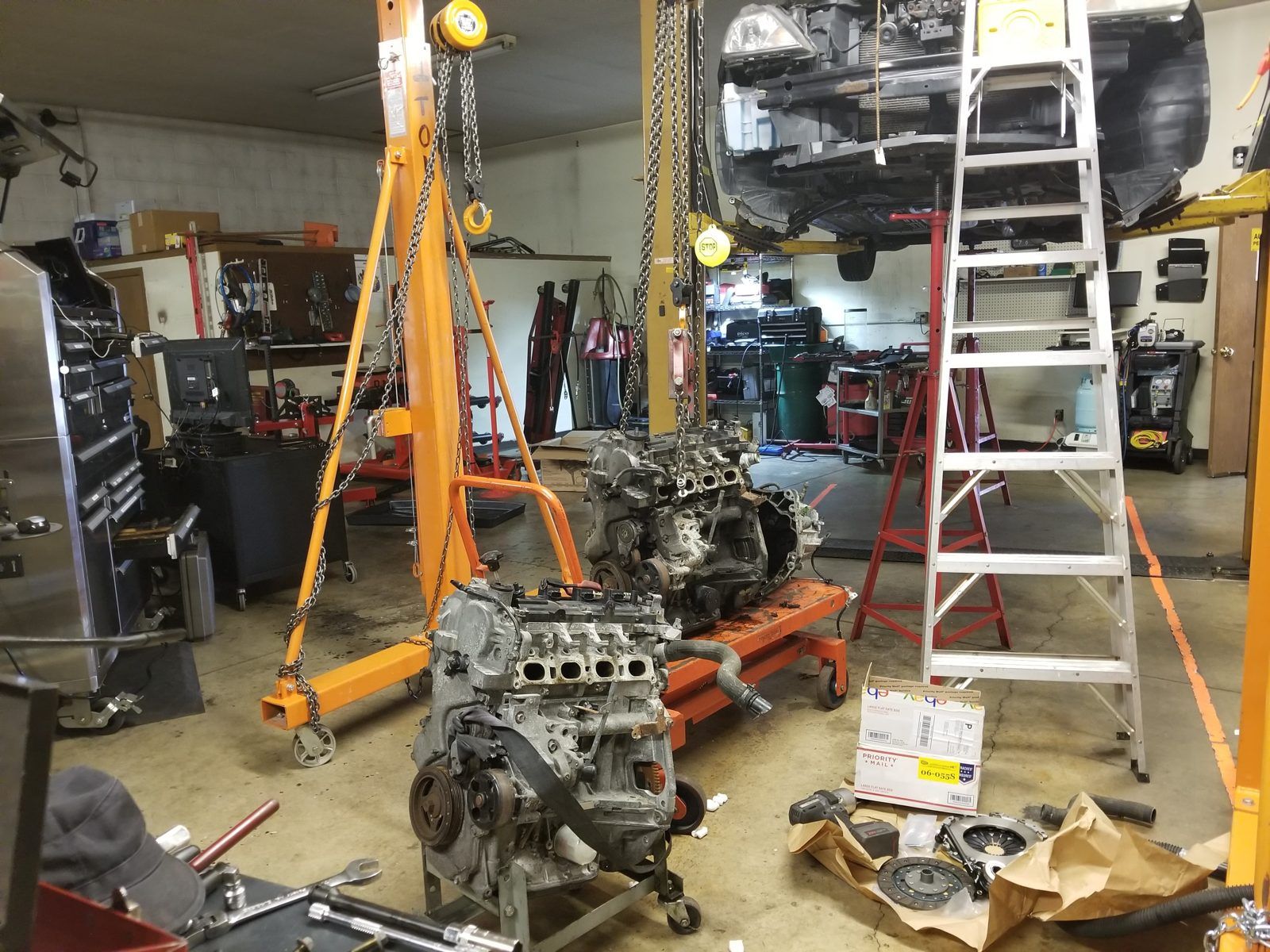 Engine and transmission assembly suspended from a chain hoist during removal at Speedy Underhood Service in Columbus, Ohio