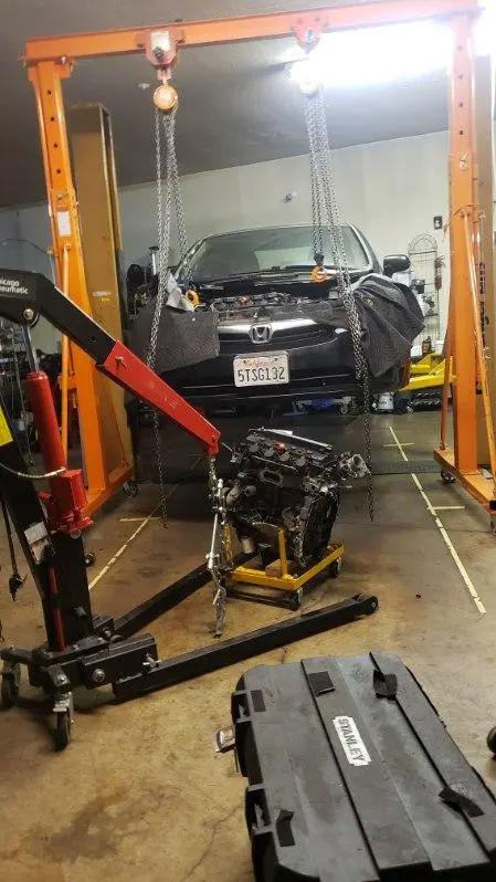 Engine lowered out of a Honda sedan on an engine hoist during an engine replacement at Speedy Underhood Service in Columbus, Ohio