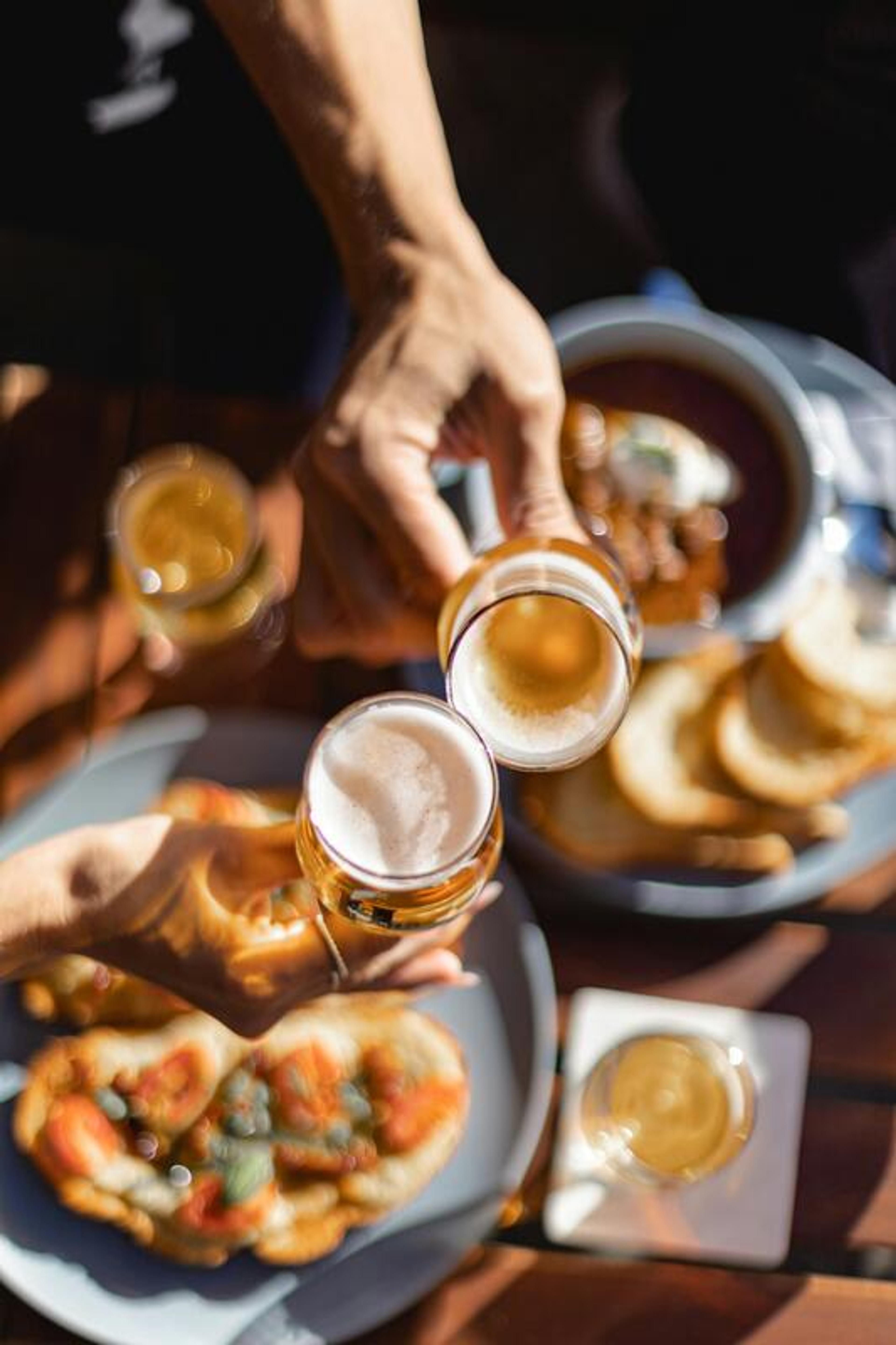Friends toasting beers over food at the taproom