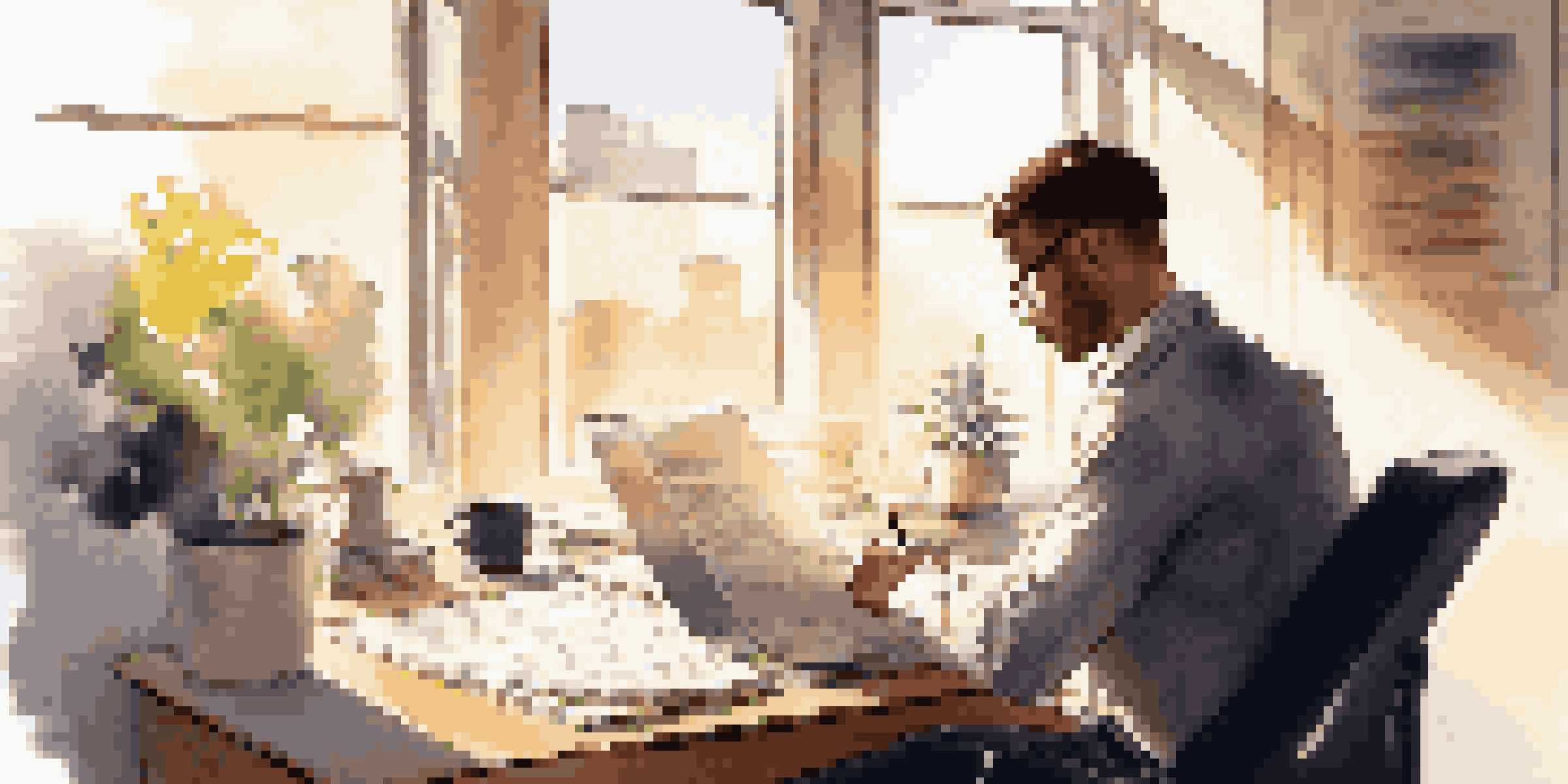 A young professional working on their resume at a desk with sunlight coming through a window.