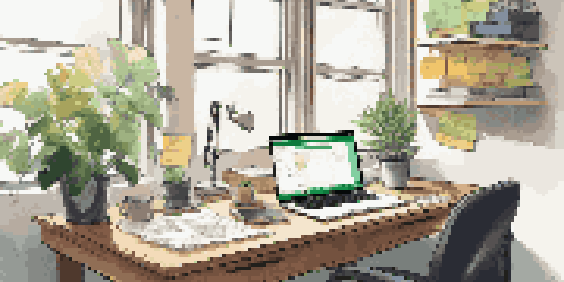 A modern workspace with a laptop, colorful post-it notes, a coffee mug, and a green plant, illuminated by soft natural light.