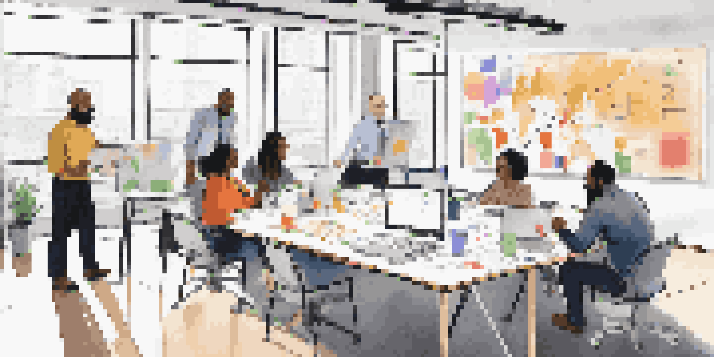 A group of diverse professionals working together in a modern office, collaborating around a large table with laptops and notes.