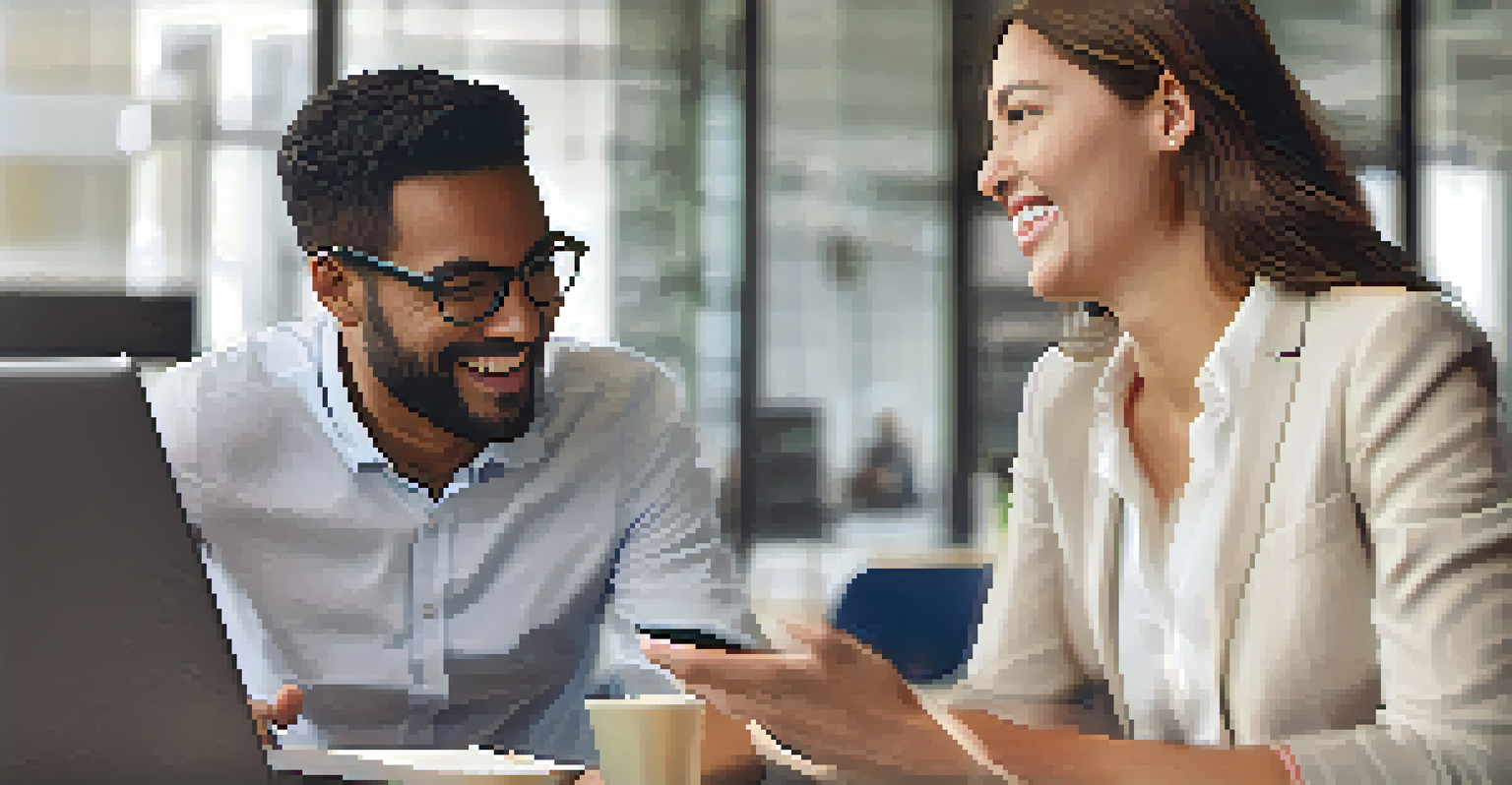 Close-up of two colleagues giving constructive feedback, one smiling and pointing at a laptop screen while the other listens attentively.