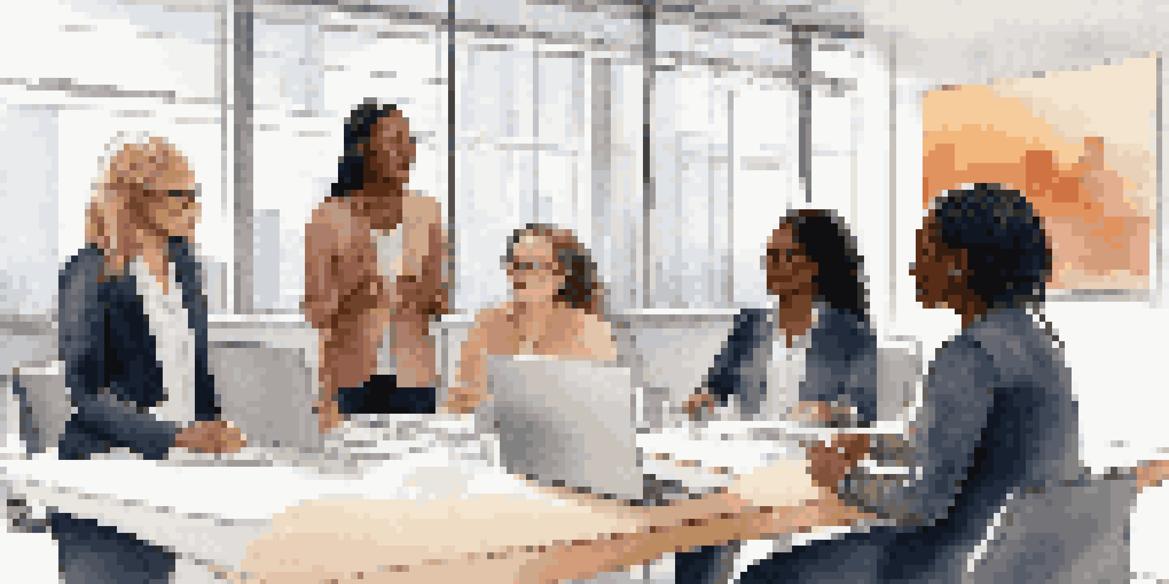 A diverse group of women leaders collaborating in a bright modern office, discussing a digital presentation.