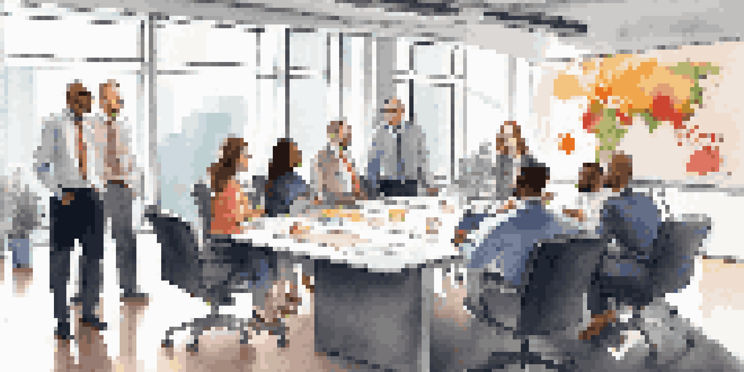 A diverse group of professionals participating in a team meeting in a bright, modern office, with a whiteboard and diagrams in the background.