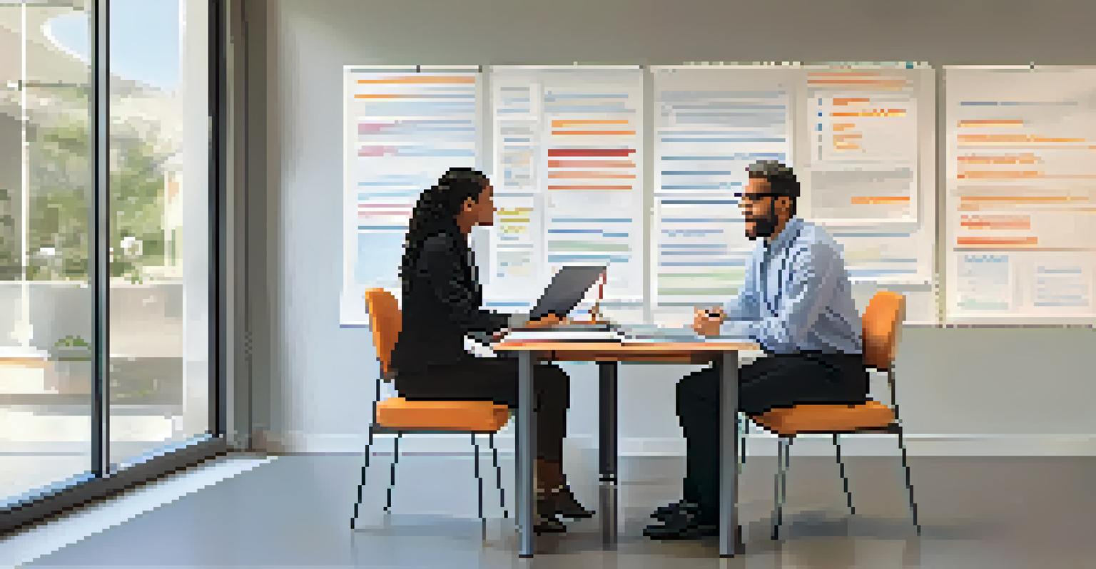 A mentor providing feedback to a mentee in a bright office, with documents and a laptop on the table.