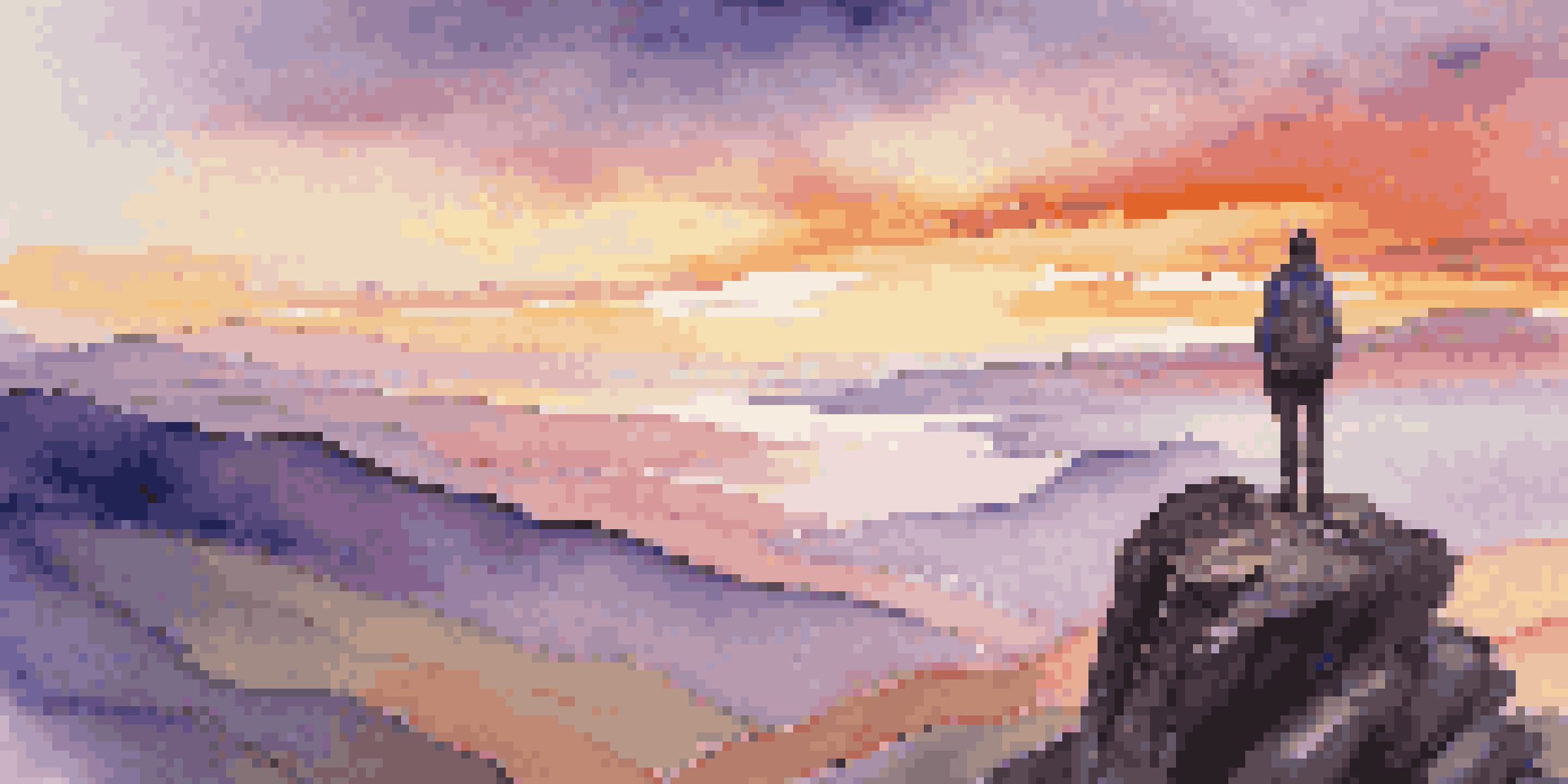 A person in casual hiking attire stands on the edge of a cliff, looking over a valley at sunset with vibrant colors in the sky.