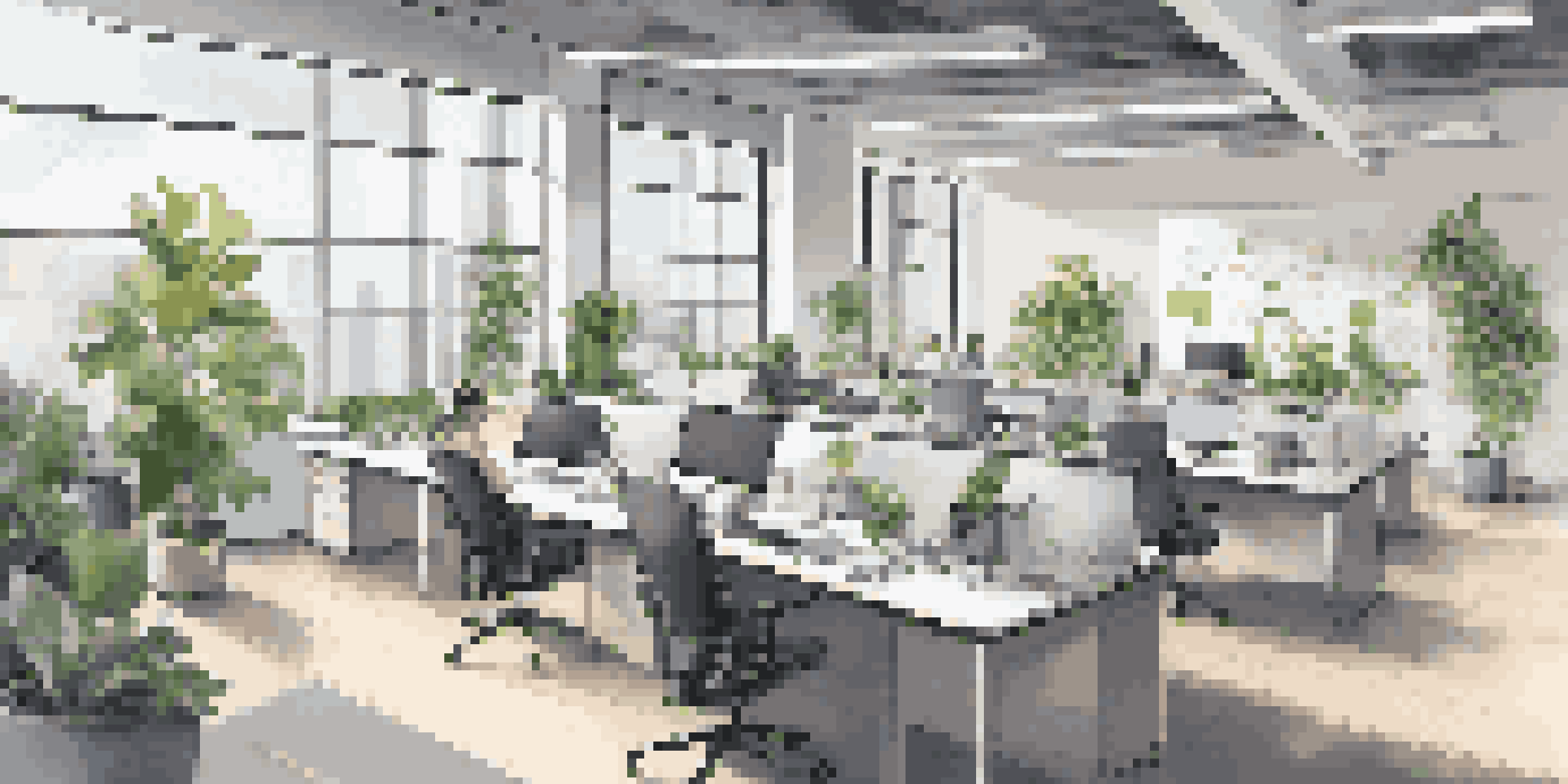 A bright and modern open office space with desks, laptops, and plants, illustrating a digital-first workplace.