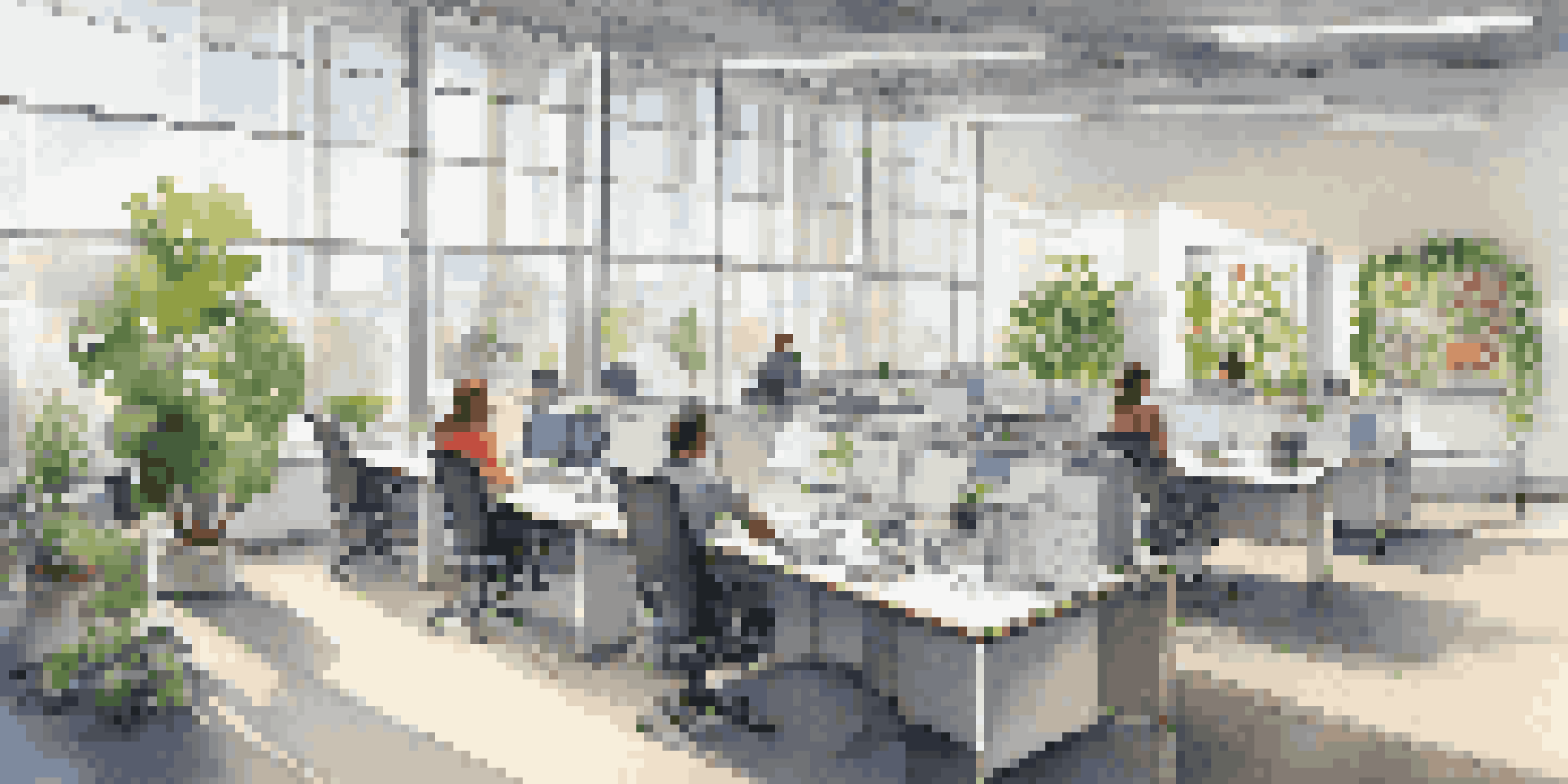 A bright and modern office showing ergonomic furniture and employees collaborating around adjustable desks.