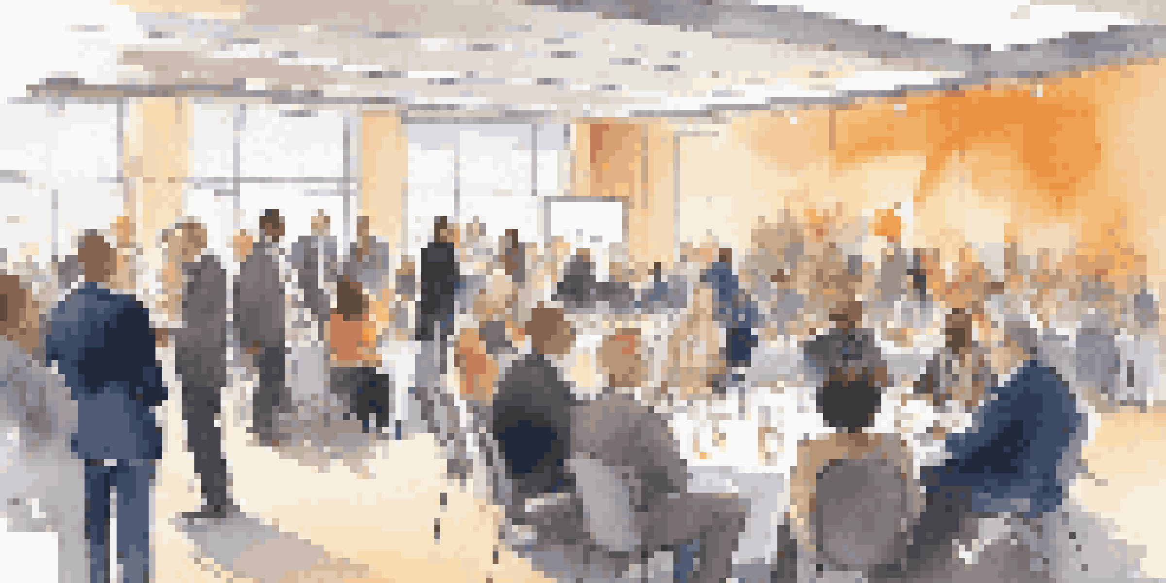A lively networking event with diverse professionals in business attire conversing in a bright conference hall.