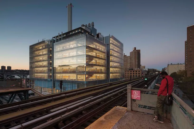 a man is standing on a bridge over train tracks in front of a large building .