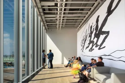 A group of people are sitting in a room with a large mural on the wall
