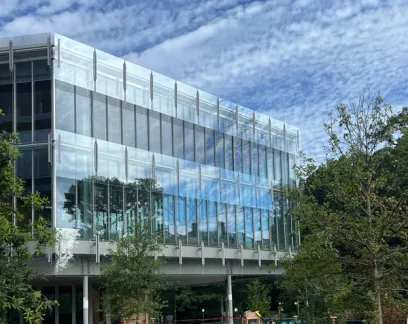 a large glass building with a lot of windows is surrounded by trees .