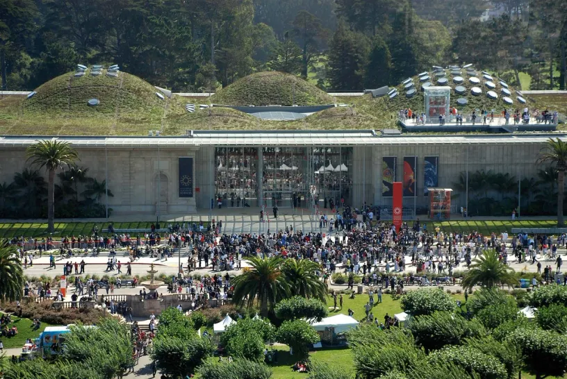 a large crowd of people are gathered in front of a large building with a green roof .