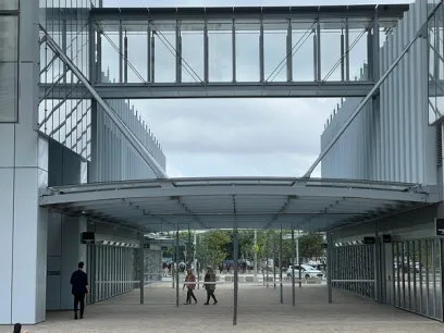 A group of people are walking under a bridge between two buildings
