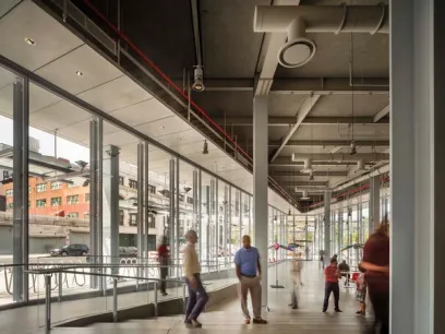 a group of people are standing in a large room with a lot of windows .