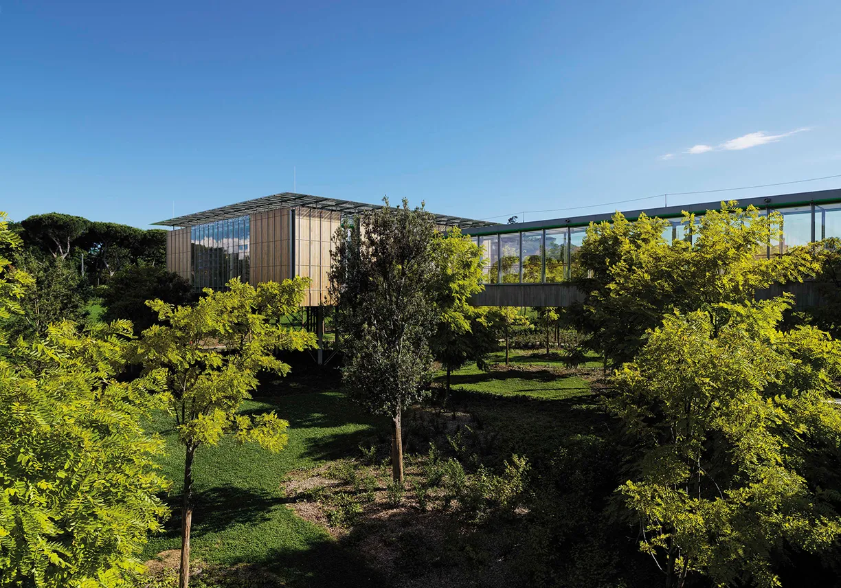 A large building with a lot of windows is surrounded by trees and grass