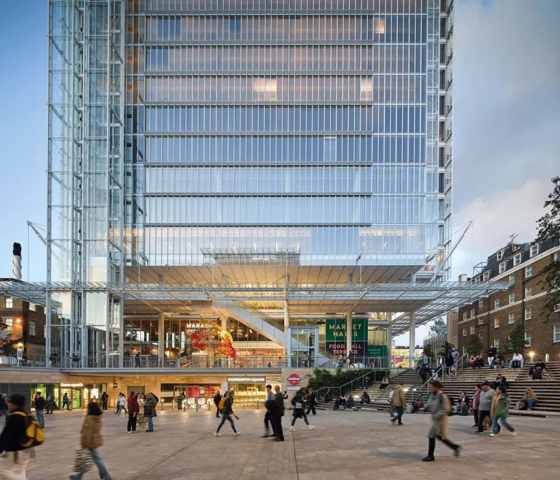 Modern glass skyscraper overlooking a busy public square with people walking and sitting on broad steps.