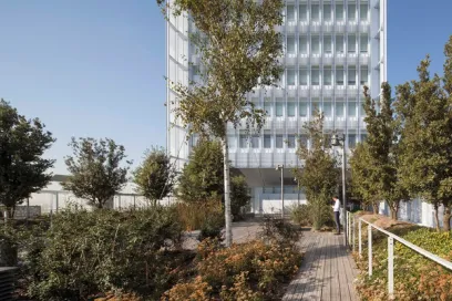 A woman is walking down a wooden walkway in front of a tall building