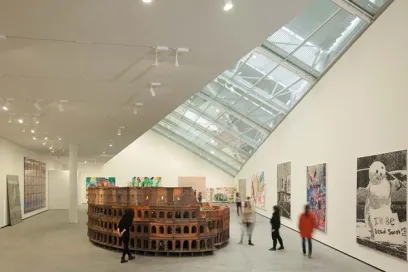 A group of people are standing around a model of the colosseum in a museum