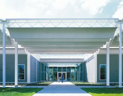 A man and a woman are walking under a canopy into a building