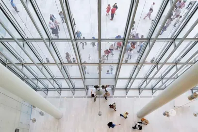 A large group of people are walking through a large glass building
