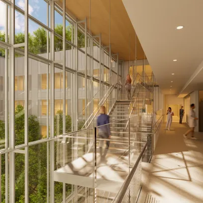 Modern building interior with a multi-level glass staircase and a glass wall viewing an atrium with trees. People move through the sunlit space.