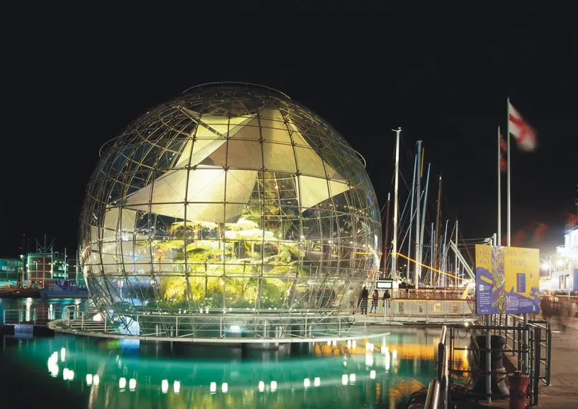 A large glass dome in the middle of a body of water at night