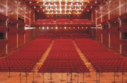 A large auditorium filled with red seats and microphone stands