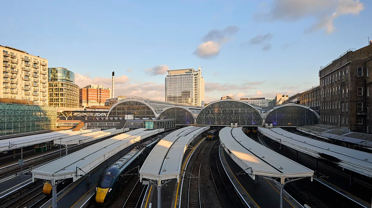 A train station with a lot of tracks and buildings in the background