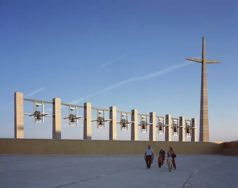 A group of people are walking in front of a large cross