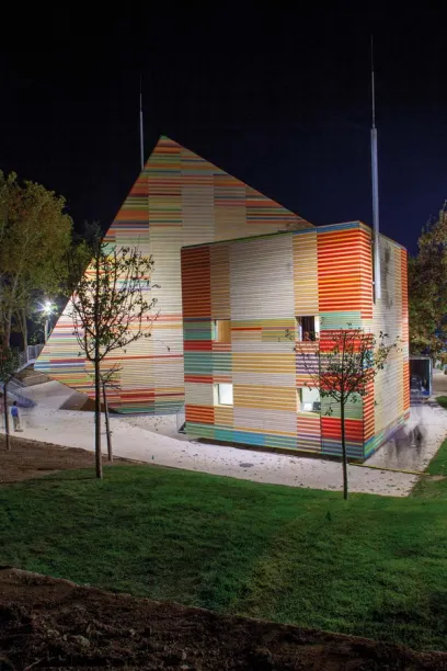 a colorful building with a pyramid shaped roof is lit up at night