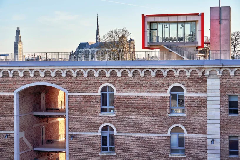 An aerial view of a brick building with a balcony on the roof