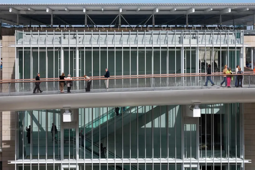 A group of people are walking across a bridge in front of a building