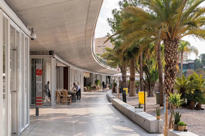 A group of people are sitting at tables outside of a building next to palm trees