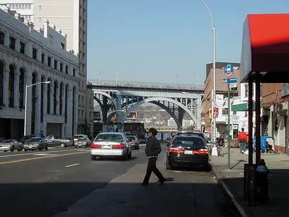 a man is walking down a city street next to a bus stop .