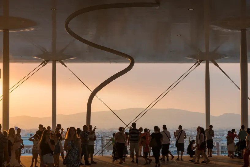 a group of people are standing under a canopy looking at the sunset .