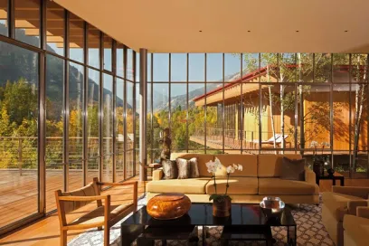 A living room with a couch , chairs , and a lot of windows